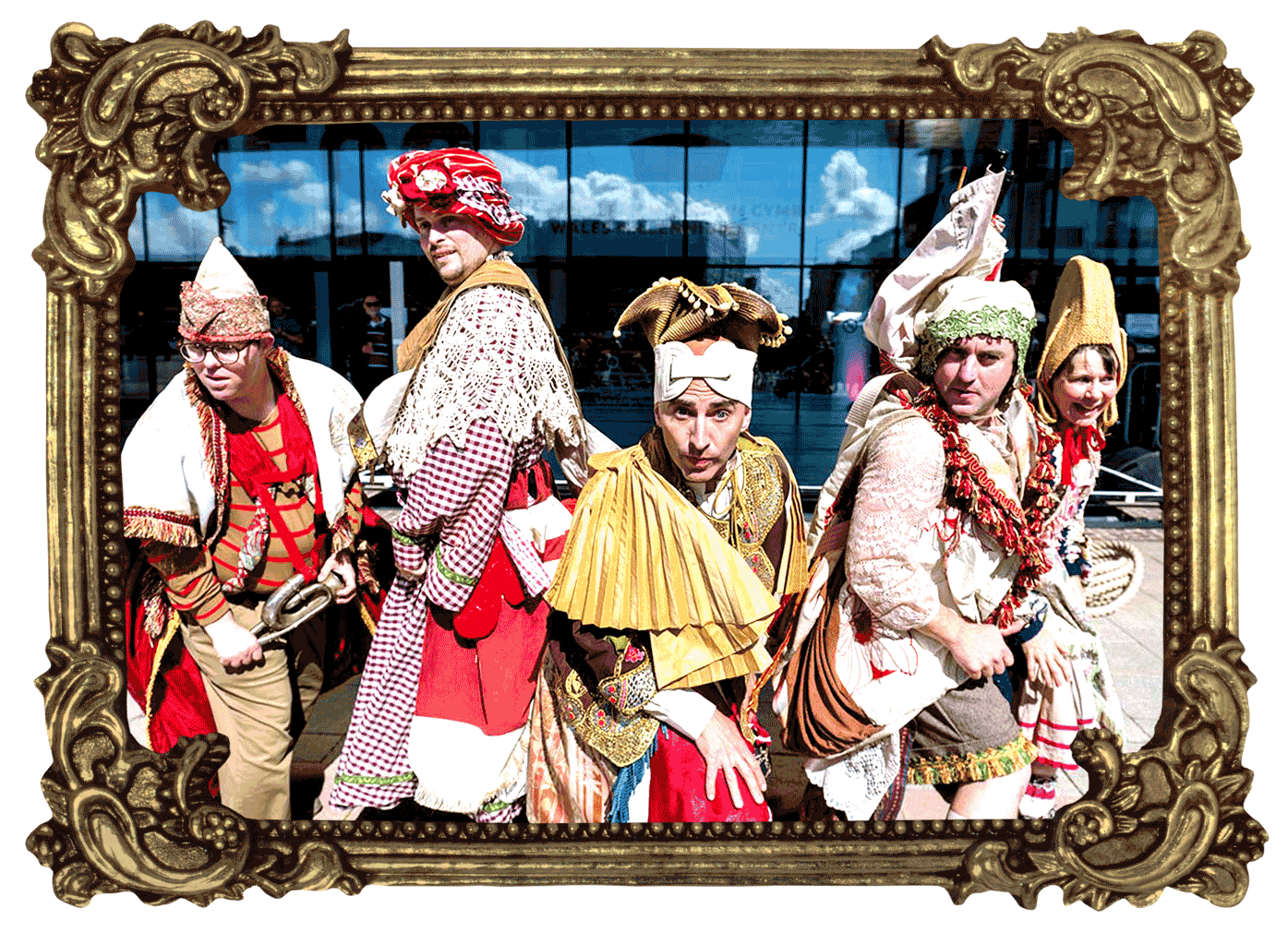  Four men and a woman in colourful costumes are primed for action- weight on their front legs as they gaze outwards. Behind them, the glass front of a large building reflects the sky.